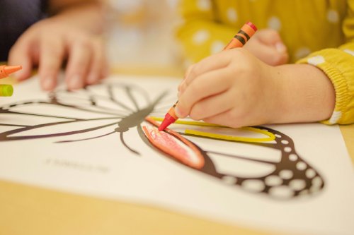 Child coloring a butterfly with crayons